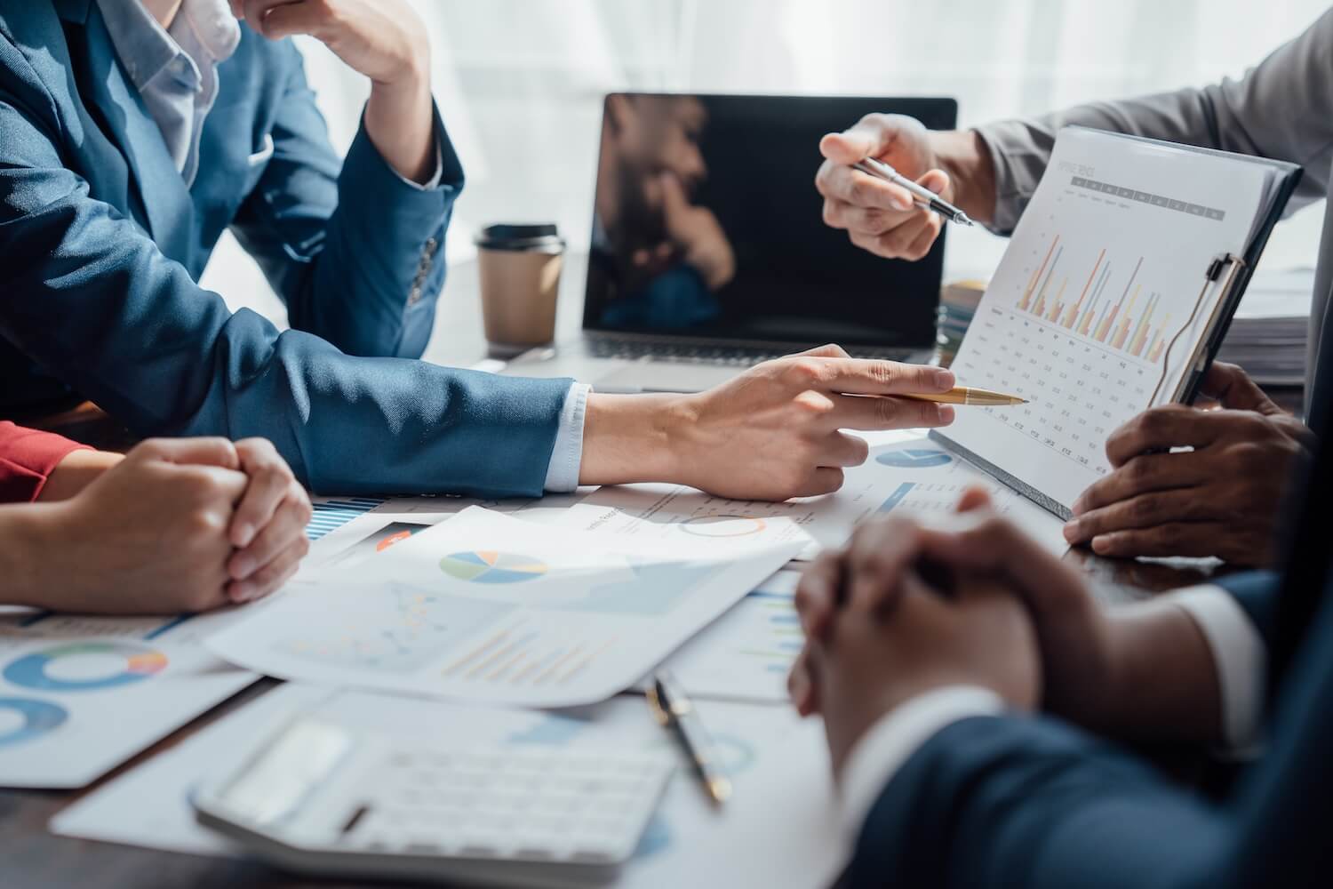 Conseillers et clients examinant autour d'une table des graphiques de prévoyance et des projections de retraite