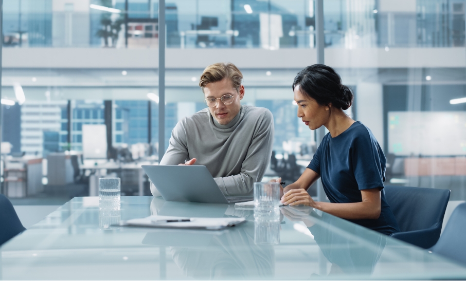 Two professionals reviewing finances on a laptop in a modern office