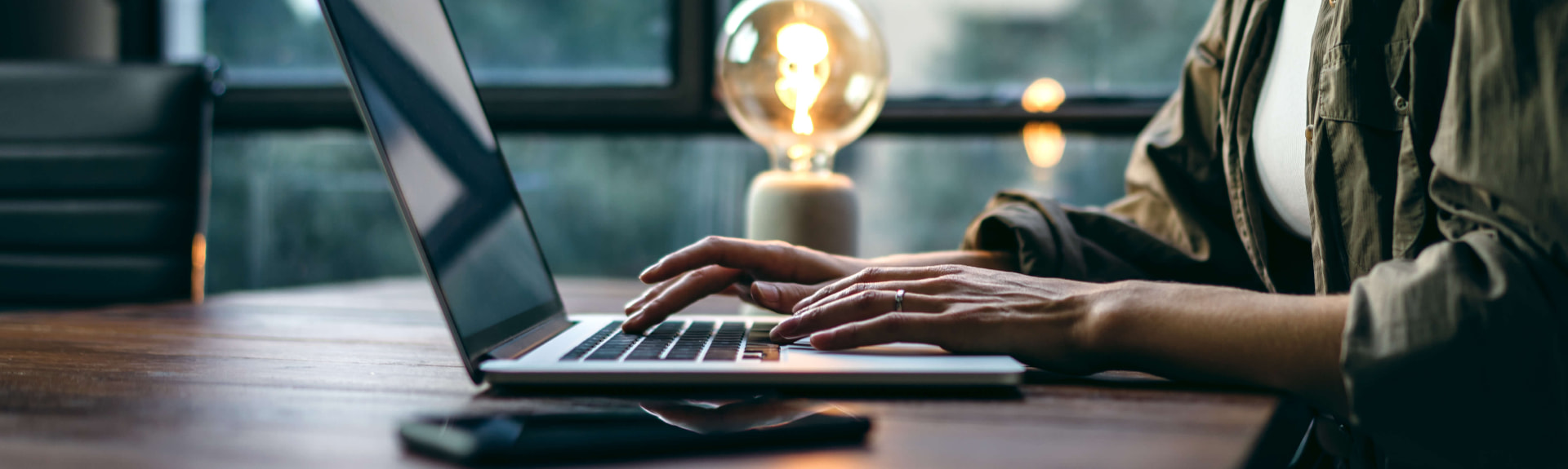Fondateur travaillant sur un ordinateur portable à un bureau en bois dans un bureau chaleureusement éclairé le soir