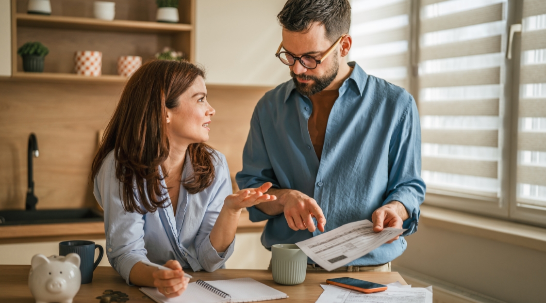 Un couple passe en revue son budget mensuel à la table de la cuisine