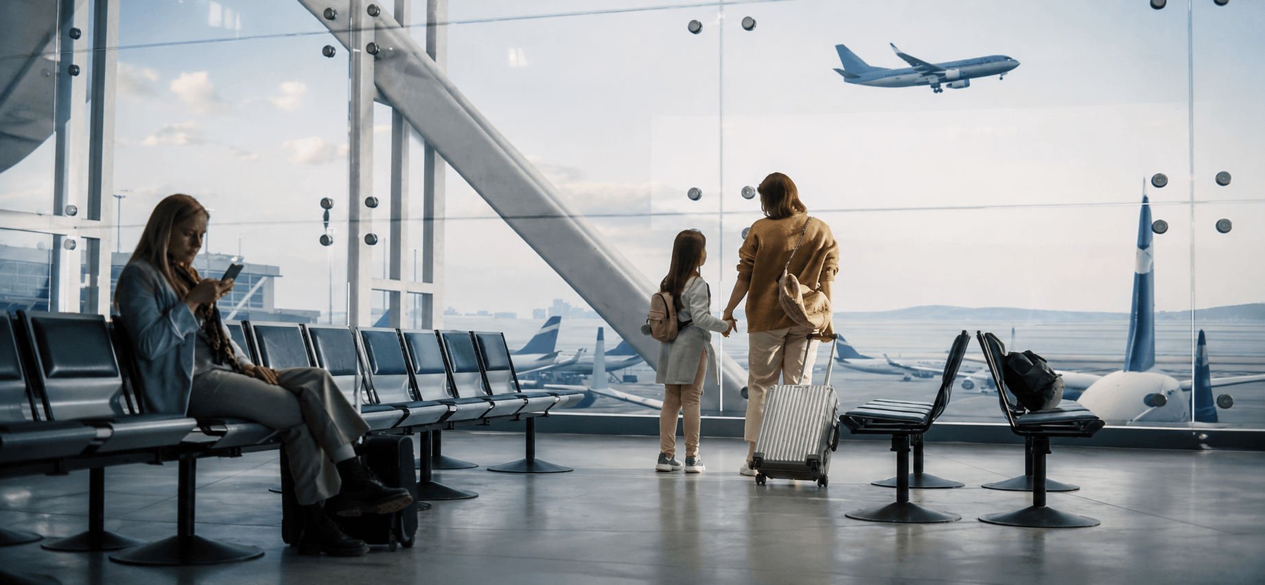 Mère et fille regardant un avion décoller depuis la fenêtre d'un terminal d'aéroport