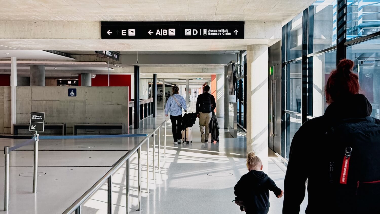 Une famille avec des bagages traversant le hall d'arrivée d'un aéroport suisse