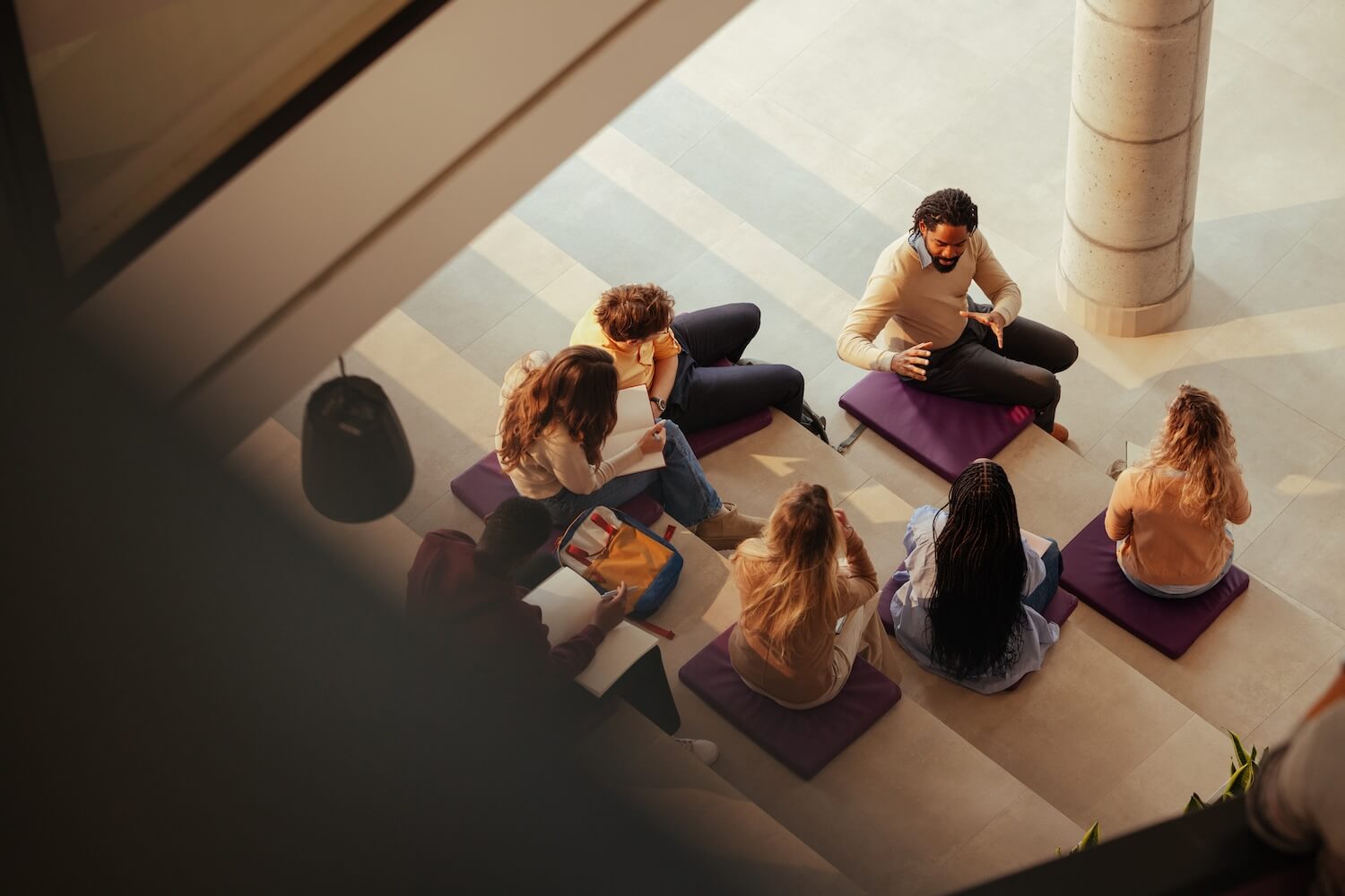 Des élèves assis en cercle avec un enseignant dans un bâtiment scolaire suisse lumineux