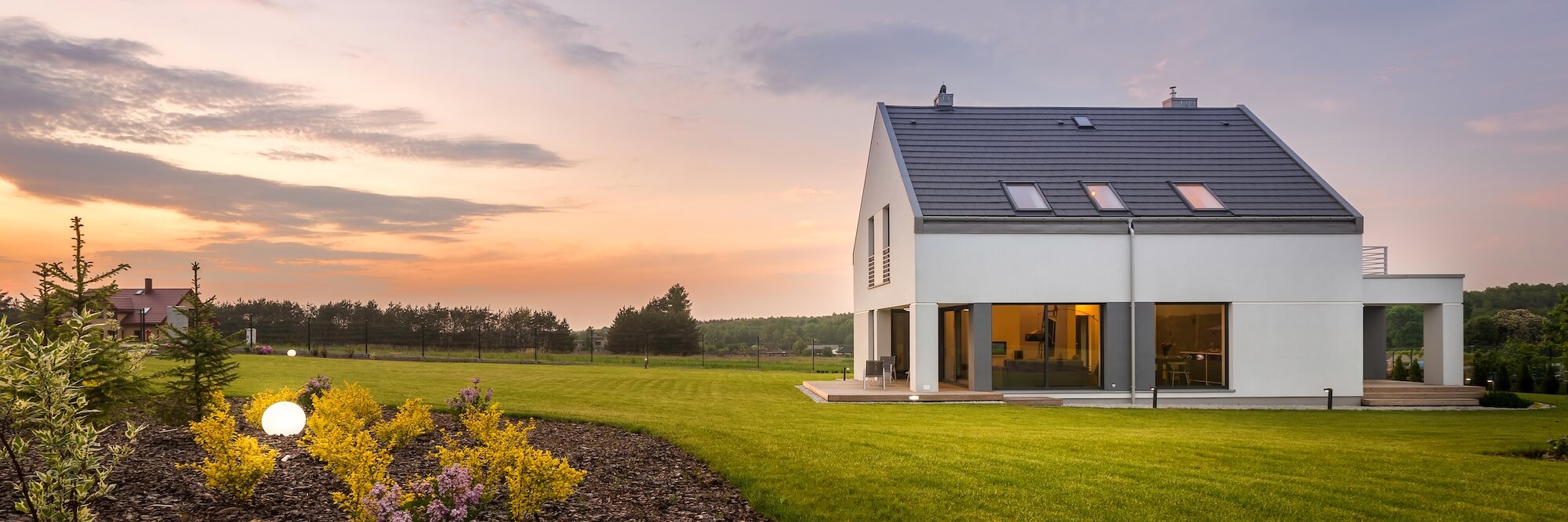 Maison individuelle moderne avec une grande pelouse au coucher du soleil