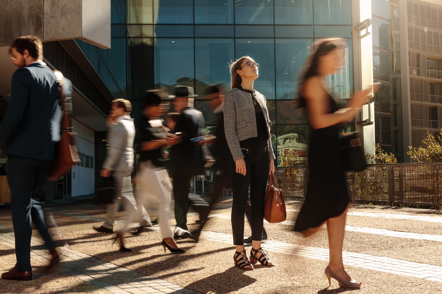 Des professionnels passent devant un immeuble de bureaux moderne dans la lumière du soir